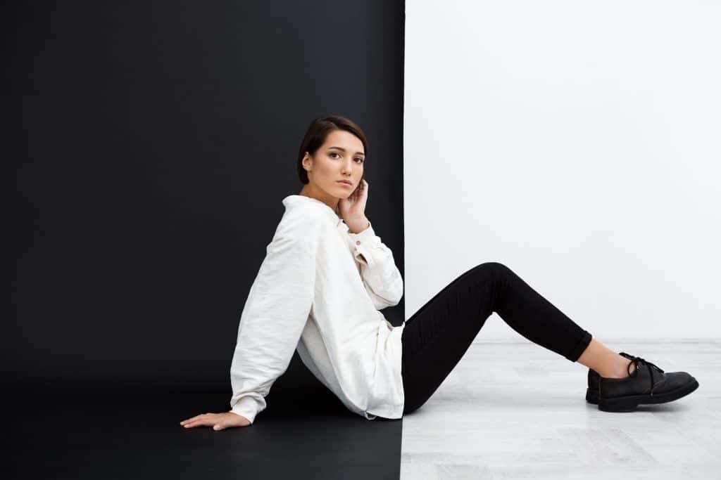 young beautiful girl sitting on floog infront of black and white wall showing a high contrast in color theory and color design